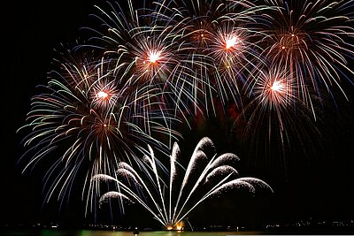 In einem Nachthimmel explodieren mehrere Silvesterraketen.