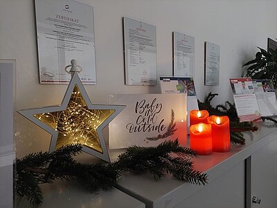 Leuchstern, rote Kerzen und eine Weihnachtskarte dekorieren das Büro.