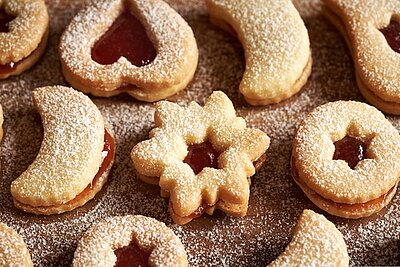 Weihnachtsplätzchen mit Marmelade und Puderzucker in verschiedenen Formen.