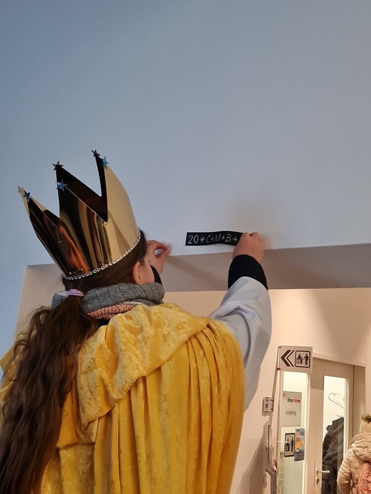 Sternsinger bringt des Schriftzug C+M+B an der Tür an