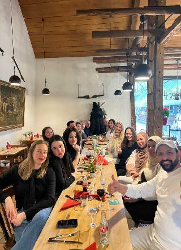 Die Teilnehmenden sitzen an einer langen Tafel und essen Pfannkuchen.