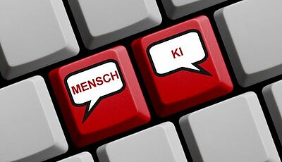 Zwei rote Tasten auf einer Computertastatur, beschriftet mit "MENSCH" und "KI", die als Sprechblasen dargestellt sind, um die Kommunikation zwischen Menschen und künstlicher Intelligenz zu symbolisieren.