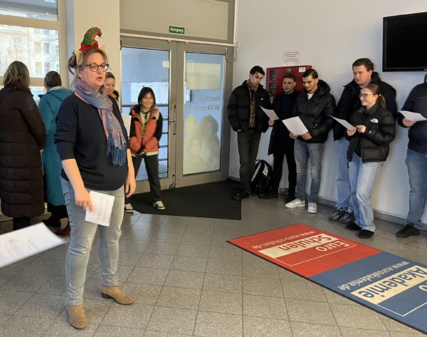 Mitarbeitende stehen im Flur der Schule und machen Lockerungsübungen.