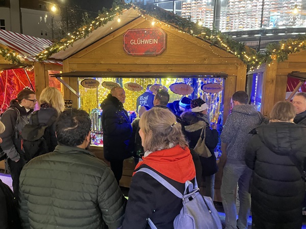 Mtarbeitende stehen vor einem Glühweinstand auf dem Weihnachtsmarkt.