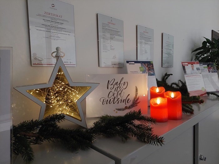 Leuchstern, rote Kerzen und eine Weihnachtskarte dekorieren das Büro.