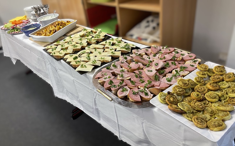 Langer gedeckter Buffettisch mit belegten Brötchen, Dips und Gebäck.